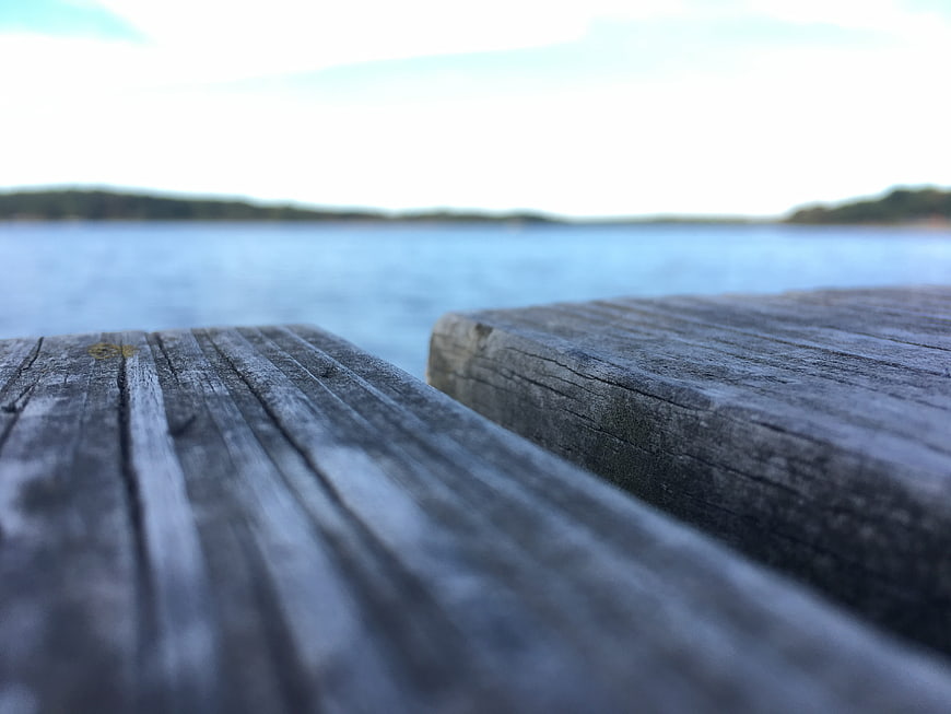 Close-up of weathered wooden dock planks with blurred lake background