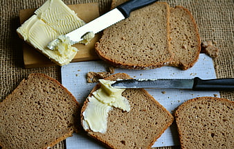 Slices of whole grain bread with butter and knife on burlap