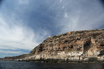 Lighthouse on rugged coastal cliffs overlooking the sea