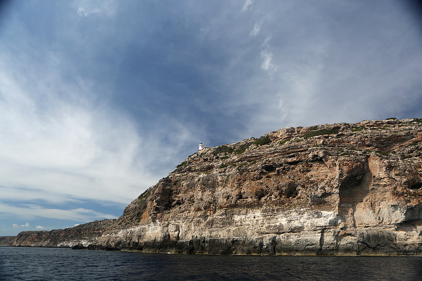 Lighthouse on rugged coastal cliffs overlooking the sea