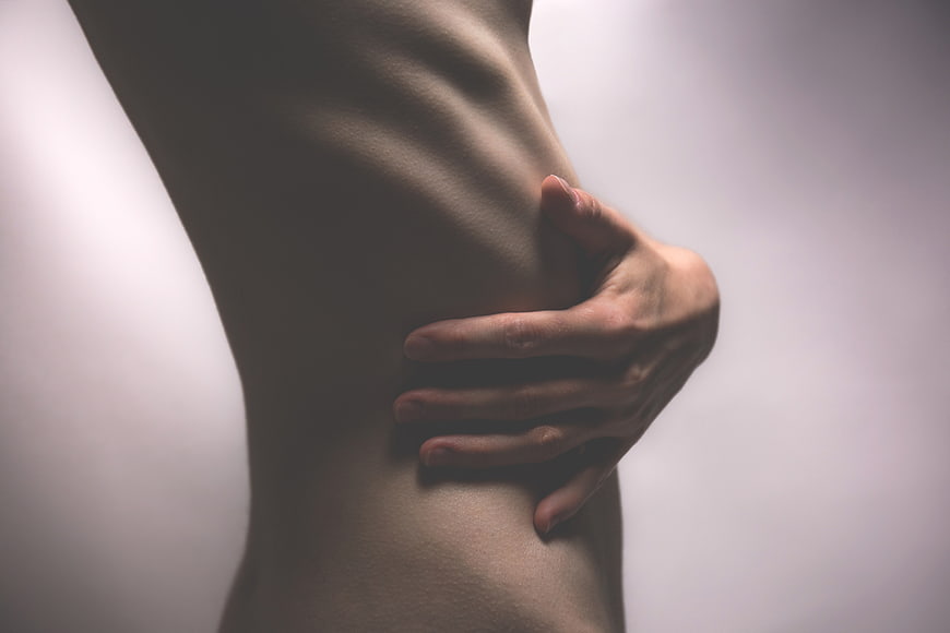 Close-up of woman's hand on ribcage torso