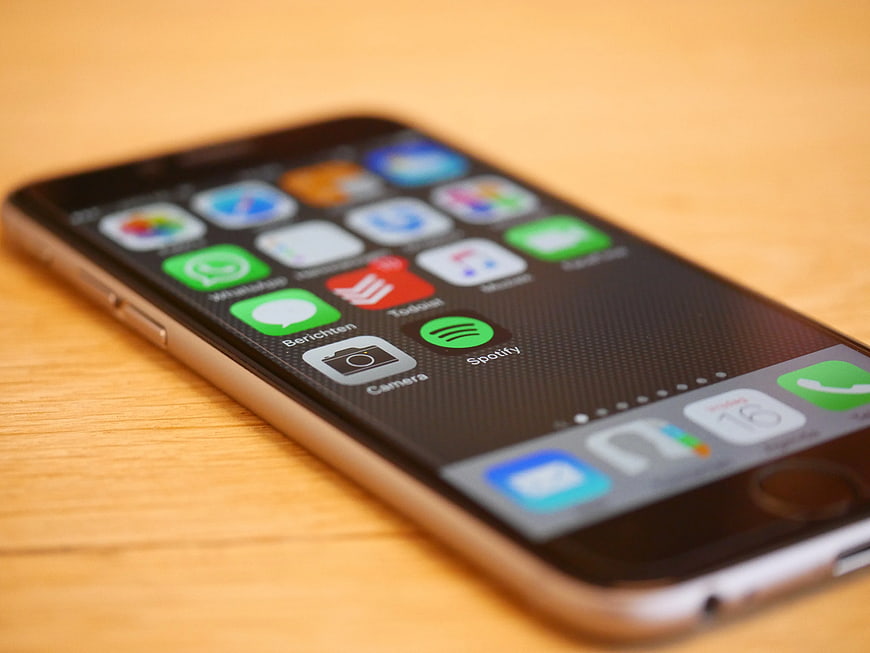 Space Gray iPhone 5s on wooden table with app icons