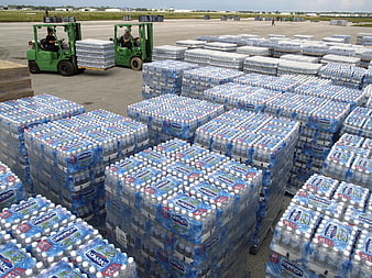 Pallets of bottled water and forklifts at outdoor hurricane relief distribution site