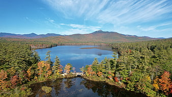 Aerial View of Serene Lake Surrounded by Autumn Forest and Mountains