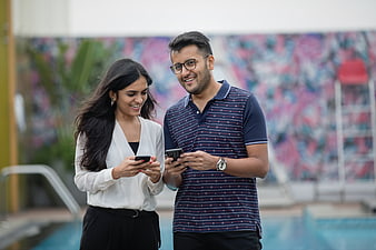 Happy Indian couple using smartphones outdoors