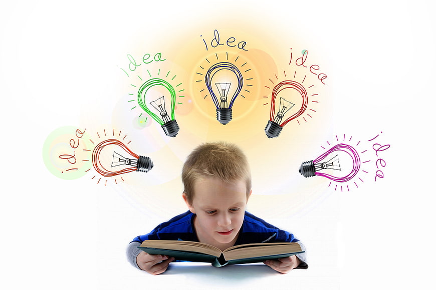 Young boy reading book with colorful lightbulb idea doodles