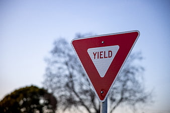 Red Yield Traffic Sign Against Blue Sky