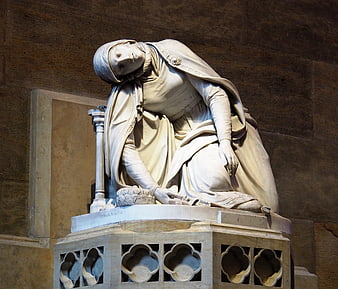 White marble statue of kneeling woman in cathedral interior