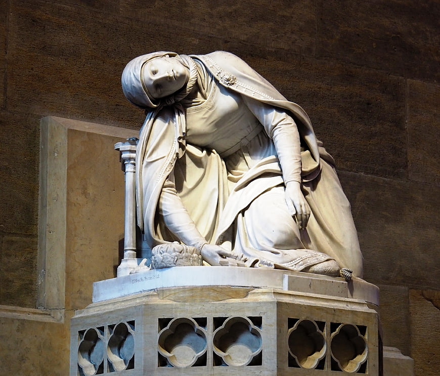 White marble statue of kneeling woman in cathedral interior
