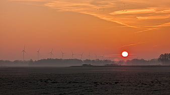 Wind Turbines Silhouette Against Orange Sunset Sky