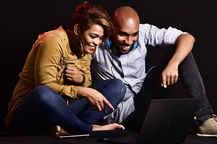 Happy Diverse Couple Laughing While Watching Laptop Content