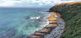 Aerial View of Scenic Coastal Beach with Turquoise Ocean and Green Cliffs