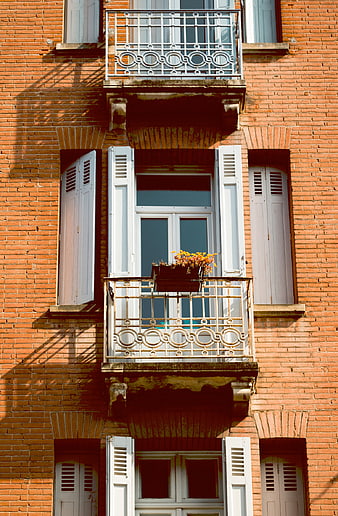 Red Brick Building Facade with White Shutters and Balcony