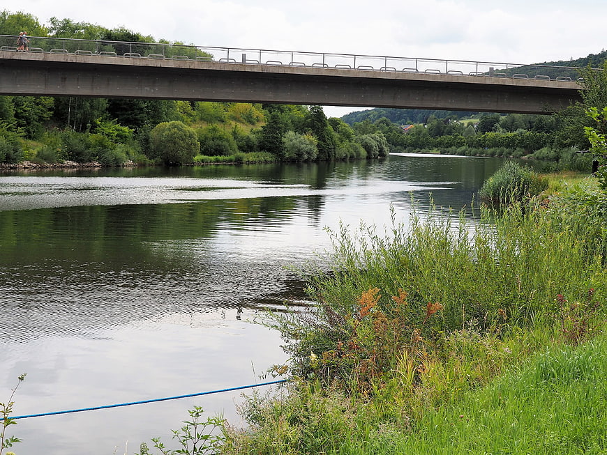 Concrete bridge over calm river with lush green banks