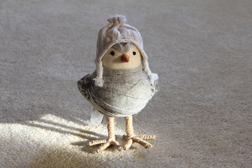 Handmade Wool Bird Doll Wearing Knit Hat on Textured Beige Background