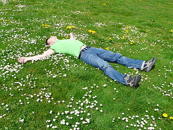 Man relaxing in a green meadow with daisies