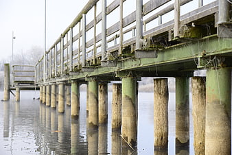 Weathered wooden pier with cobwebs over calm winter water