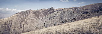 Panoramic view of rugged rocky mountain ridge with dry grass