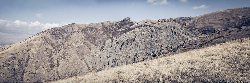 Panoramic view of rugged rocky mountain ridge with dry grass