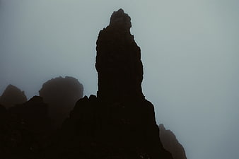 Silhouette of jagged mountain peak in thick fog