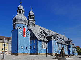 Blue Wooden Church with Gray Roofs in Town Square