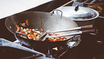 Stir-frying vegetables in a wok with tongs