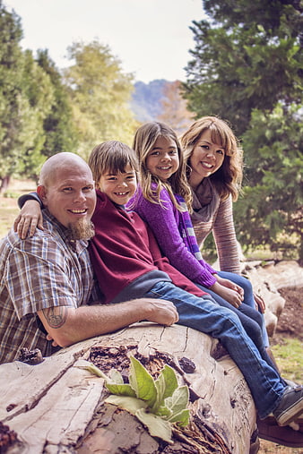 Happy family of four sitting on a log in nature