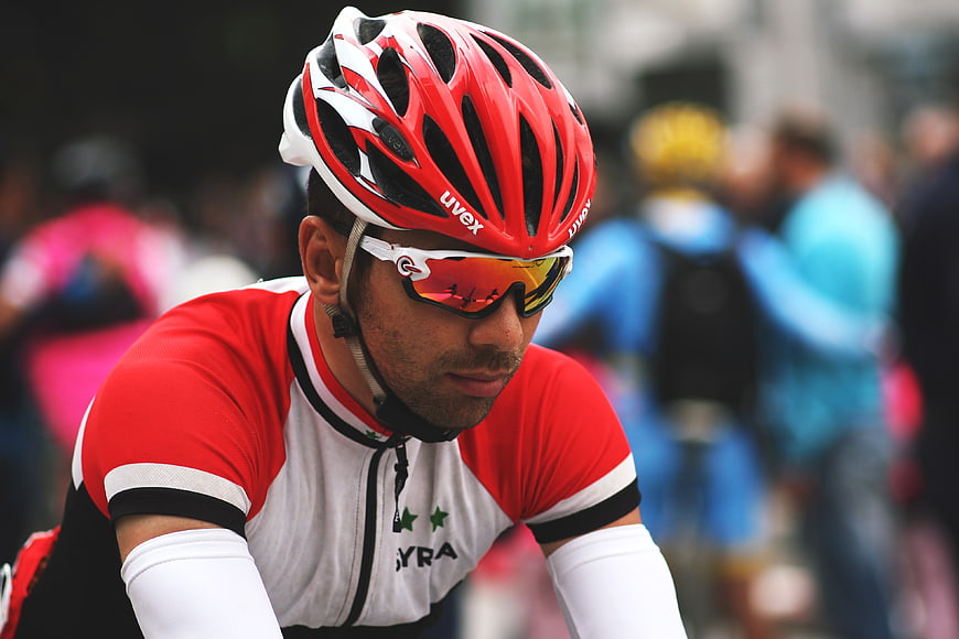 Focused male cyclist wearing red Uvex helmet and sunglasses