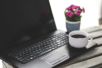 White Coffee Cup On Black Laptop Keyboard With Pink Flowers