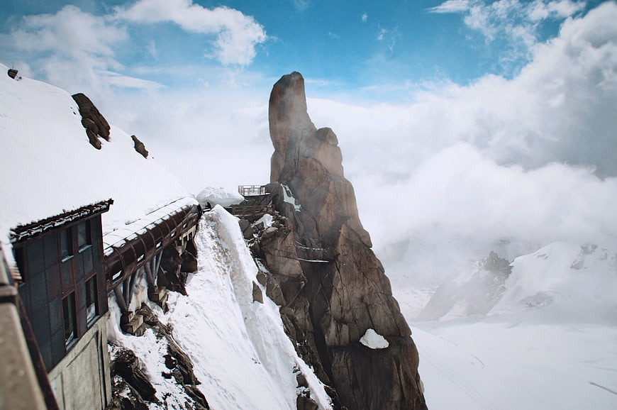 Snowy mountain peak with observation deck and clouds
