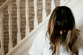 Sad woman with head down on white staircase
