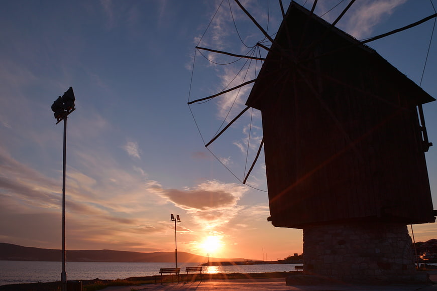 Silhouette of traditional windmill at sunset by the sea