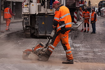 Road Construction Worker Operating Plate Compactor on Urban Street