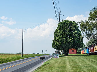 Rural Road with Colorful Train Cars and Blue Sky