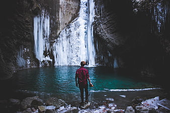 Man standing before frozen waterfall in winter canyon