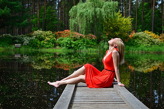 Woman in Red Dress Relaxing on Wooden Dock by Lake