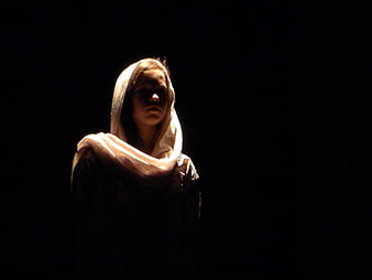 Dramatic Portrait Of Woman In White Headscarf On Dark Stage