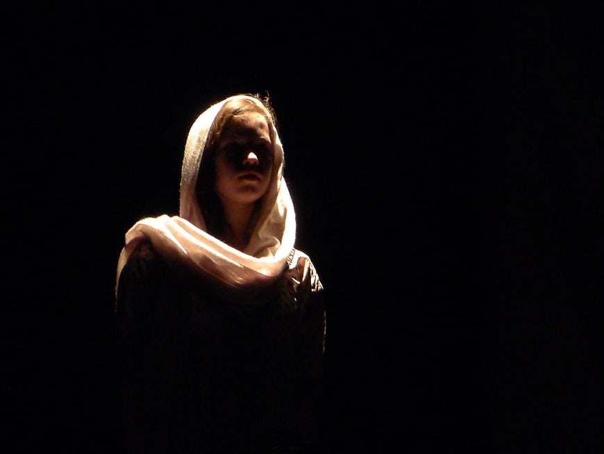 Dramatic Portrait Of Woman In White Headscarf On Dark Stage