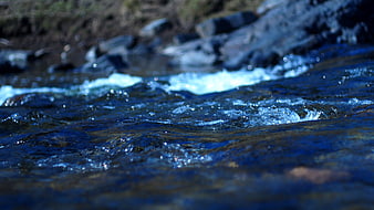 Close-up of flowing blue river water with rocks