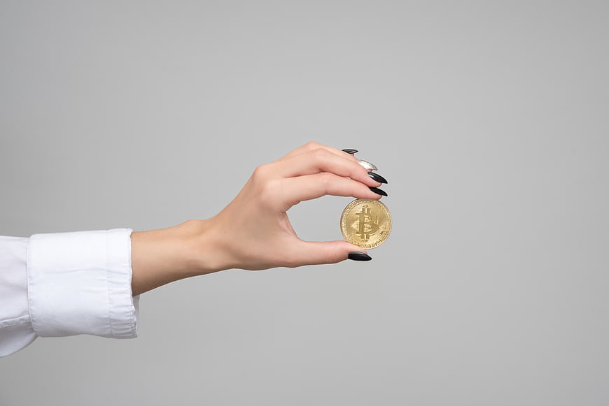 Woman's Hand Holding Physical Bitcoin Coin on Gray Background