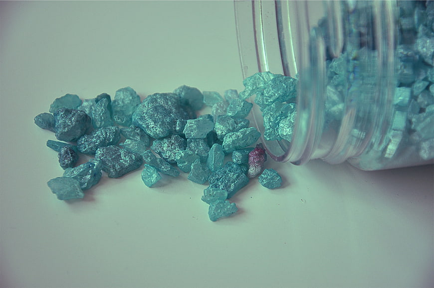 Spilled blue metallic crystals from a glass jar