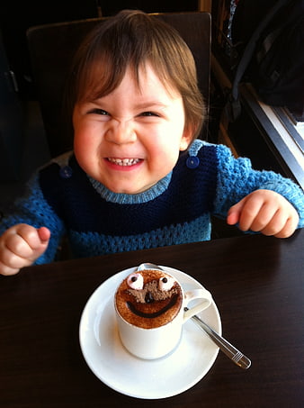 Smiling Toddler Enjoying Funny Hot Chocolate Face in Cafe