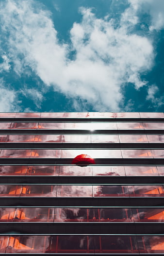 Red umbrella in modern glass building against blue sky