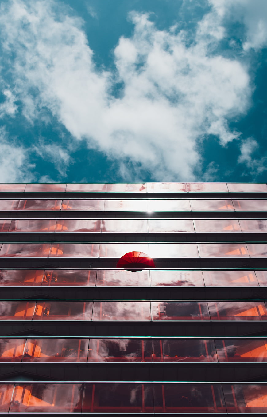 Red umbrella in modern glass building against blue sky