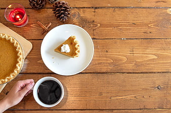 Overhead view of pumpkin pie slice and coffee on rustic wooden table