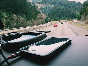Smartphone on Car Dashboard Driving on Forest Highway
