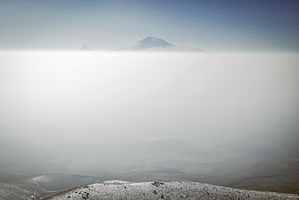 Snow-capped mountain peak rising above thick fog layer