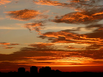 Vibrant orange sunset sky over city silhouette