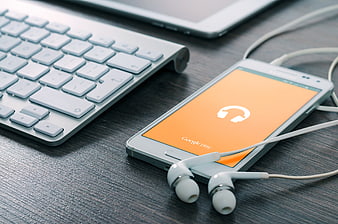 Smartphone with Google Play Music and Earphones on Desk