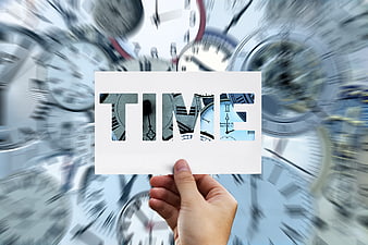 Hand holding card with TIME text against blurred clock background